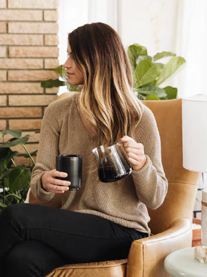 Nainen beigen paidan kanssa, jolla on baristan espressoannostelukannu lasia, moderni muotoilu, Viimeisimmät uutiset, kaikki kahvista.